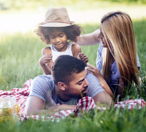 image of a family; mother and father laying on the grass with their baby overjoyed with their new Univeral Life Insurance Policy from the best insurance agency in Franklin, TN